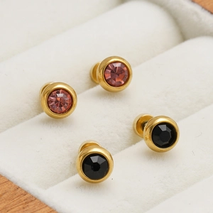 Détail macro de boucles d'oreilles en acier doré avec cristaux roses et noirs