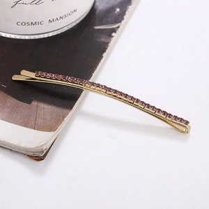 Detailed shot of golden hair clip with purple rhinestones on a minimalist background