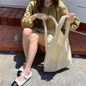 Detail of off-white lace tote bag with crochet floral patterns for women on stairs
