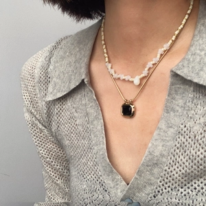 Detailed view of layered titanium steel gold snake chain and pearl necklace with square pendant