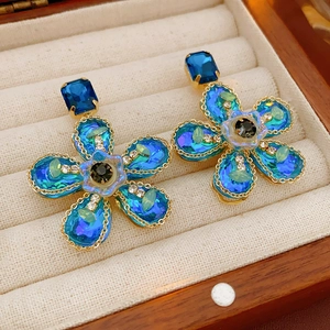 Gros plan de boucles d'oreilles fleurs vintage bleues dans une boîte en velours beige