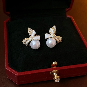 Detailed shot of bow earrings with pearls and crystals in a red velvet jewelry box