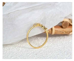 Macro shot of 18k gold plated curved ring with zircon stones on textured background