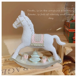 Detail of white resin rocking horse with pink saddle and festive Christmas gift boxes