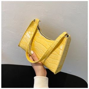 Detail shot of yellow faux leather underarm bag featuring a textured crocodile pattern