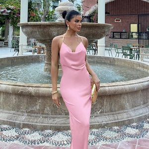 Détail d'une robe longue en satin rose avec bretelles chaîne près d'une fontaine élégante