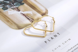 Detailed view of large gold heart-shaped hoop earrings with textured spiral thread finish