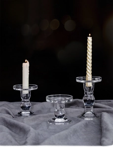 Macro detail of three clear glass pillar candle holders on dark grey velvet fabric