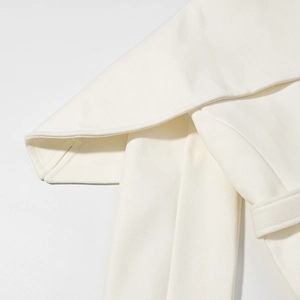 Detailed close-up of cream wool coat shoulder layers and textured matching belt