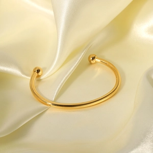 Minimalist 18K gold plated stainless steel open bangle with spherical ends on satin