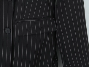 Gros plan détaillé du tissu à rayures verticales et du bouton noir d'une veste blazer