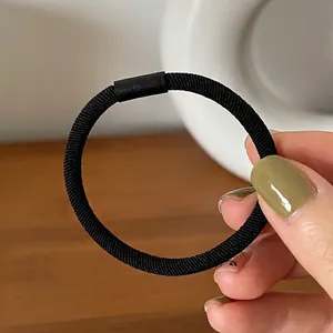 Close-up of black high-elastic hair tie with matte connector on hand-held display