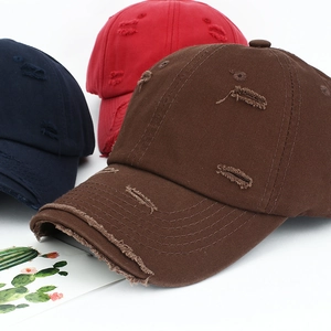Detail showing distressed cotton baseball caps in navy blue, red, and brown colors