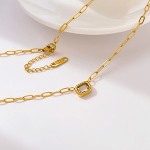 Macro shot of 18K gold-plated titanium chain featuring a clear rectangular zircon pendant