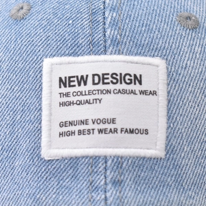 Front view of washed denim baseball cap with a white woven patch and frayed edges