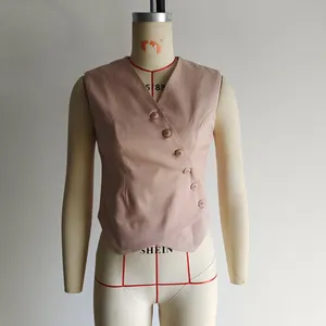 Detail of pink-brown asymmetrical vest with five matching buttons on textured fabric