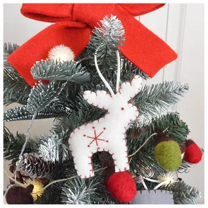 Close-up of white felt reindeer ornament with red stitching on a decorated Christmas tree