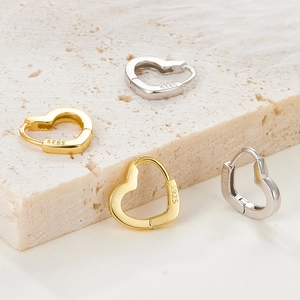 Detailed view of gold and silver S925 sterling silver heart earrings on stone