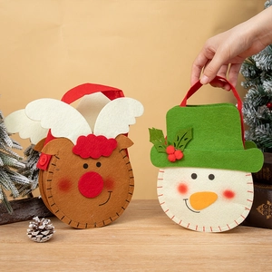 Felt Christmas gift bags featuring reindeer and snowman designs on a wooden table