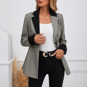 Détail du blazer gris contrasté avec revers noirs et accessoire de ceinture dorée