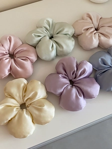 Detailed shot of six pastel satin silk flower scrunchies in varied soft macaron colors