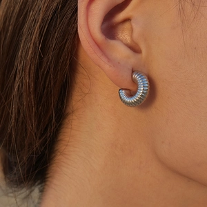 Macro shot of silver stainless steel hoop earring featuring a classic spiral texture