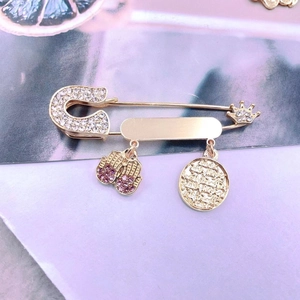 Detailed view of gold pin brooch featuring pink rhinestone boxing gloves and crown charm