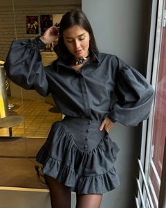 Detail of dark gray suit featuring puff sleeves, buttoned bodice, and ruffled hem skirt