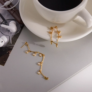 Détail de boucles d'oreilles pendantes plaquées or 18K avec zircons blancs et pampilles