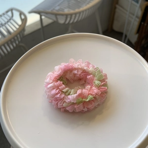 Gros plan détaillé du chouchou en dentelle rose et vert clair avec texture à volants plissés