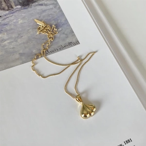 Detailed view of a gold waterdrop pendant with fluid design on a white book