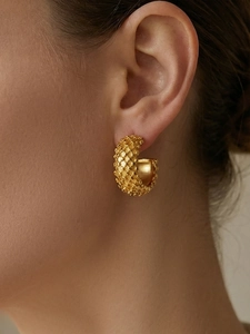 Close-up of gold-plated C-shape hoop earrings with textured scale pattern on model