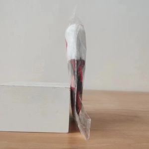 Detail of red and black plaid Christmas decoration with white faux fur trim in packaging