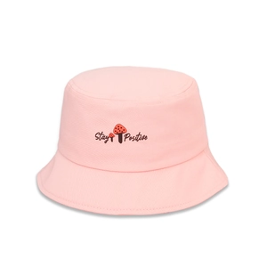 Détail d'un bob en coton rose avec motif de champignon et texte Stay Positive brodé