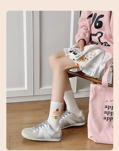 Détail de chaussette en coton blanc avec broderie gâteau cerise et bordure à volants