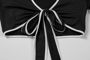 Detail of the tie-front bow with white contrast piping on a sexy black cropped shirt