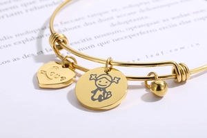 Macro shot of gold adjustable heart charm bracelet with Love engraving and girl charm