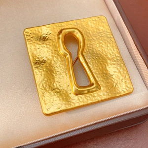 Macro shot of vintage gold square brooch with keyhole cutout in jewelry gift box