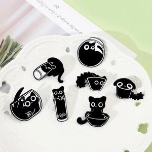 Detailed collection of black enamel cat pins displayed on a white decorative ceramic plate