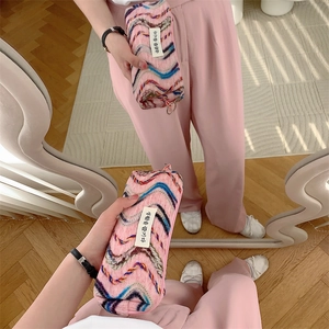 Vue détaillée d'une trousse de maquillage en tricot rose avec broderie arc-en-ciel