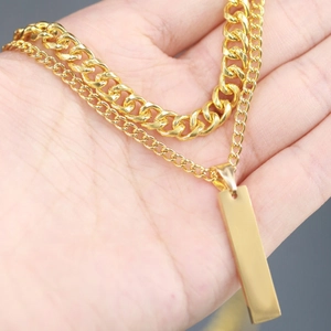 Detail of double-layer gold Cuban chain necklace with smooth rectangular pendant