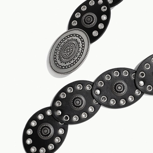 Dettaglio di cintura larga vintage da donna con borchie argentate e fibbia incisa
