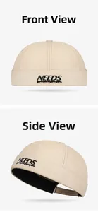 Détail de la broderie NEEDS sur un bonnet docker beige avec sangle ajustable