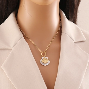 Detail of a gold stainless steel necklace featuring a shell pendant with a fish motif
