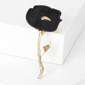 Detail of elegant black acrylic flower brooch with gold petals and metallic stem