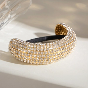 Close-up of golden elastic hair ring with sparkling pavé crystals on marble surface