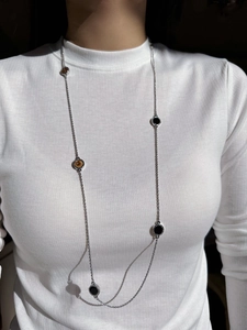Detailed view of long silver twisted chain necklace with black enamel circular pendant