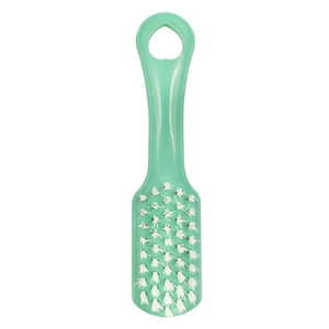 Detail of green plastic shoe brush with soft white bristles and heart-shaped hanging hole