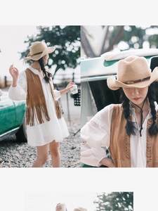 Detail of straw cowboy hat featuring leather band, beads, and feathers in a sunny setting