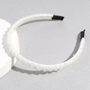 Detail of handmade white beaded headband with sparkling crystals and fabric-wrapped base